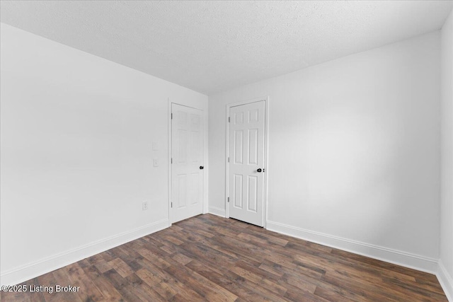 spare room with baseboards, dark wood-style flooring, and a textured ceiling