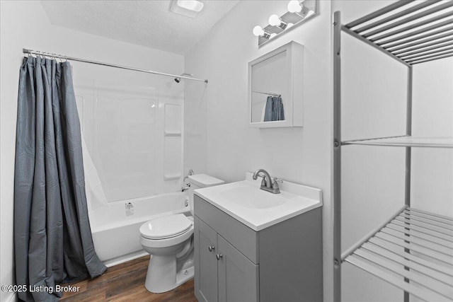 full bath featuring toilet, a textured ceiling, wood finished floors,  shower combination, and vanity