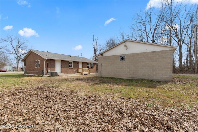 back of property featuring brick siding and central AC