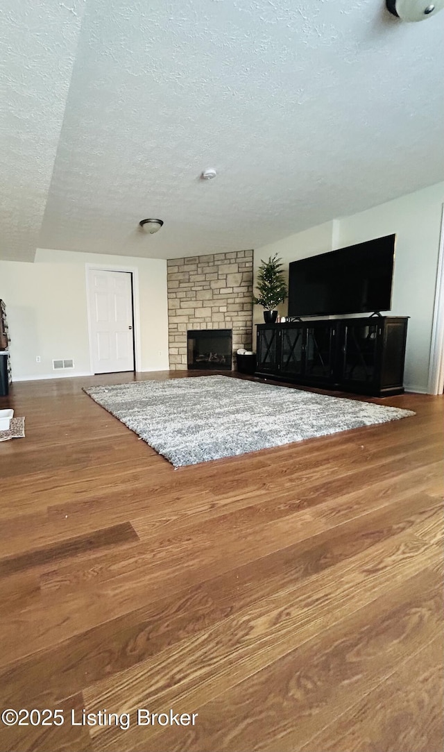 105-A Legacy Ct, Elizabethtown, KY 42701 - unfurnished living room featuring a fireplace, wood finished floors, visible vents, and a textured ceiling
