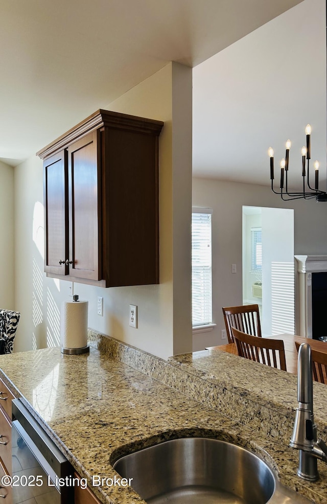 105-A Legacy Ct, Elizabethtown, KY 42701 - kitchen with light stone countertops, an inviting chandelier, a sink, dark brown cabinetry, and stainless steel dishwasher