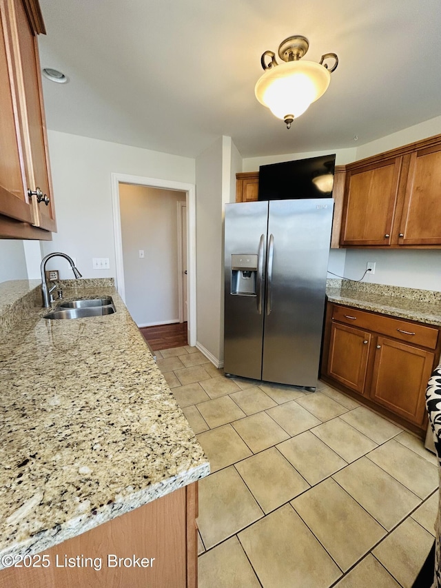105-A Legacy Ct, Elizabethtown, KY 42701 - kitchen featuring light stone counters, baseboards, a sink, stainless steel fridge, and brown cabinets