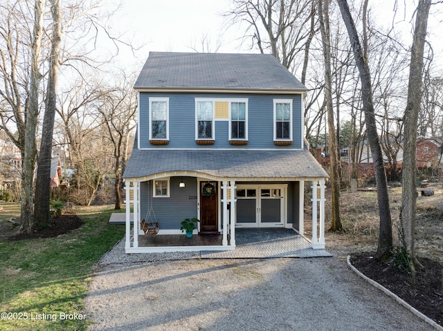 view of front of property featuring a shingled roof, covered porch, french doors, driveway, and an attached garage