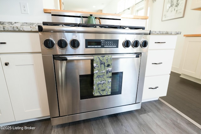 kitchen featuring light stone counters, high end range, white cabinets, and dark wood-style flooring