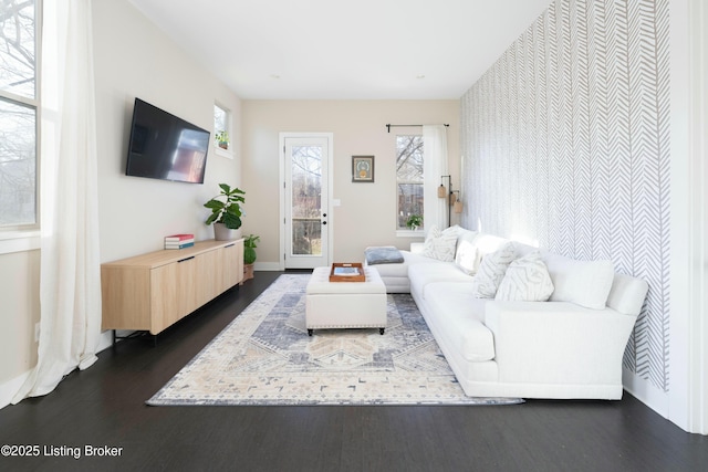 living area featuring an accent wall, dark wood-style floors, and a wealth of natural light