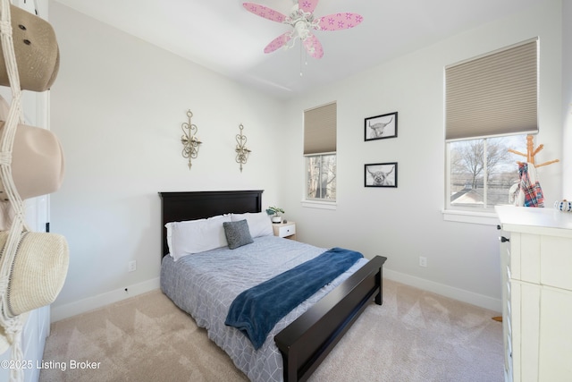 bedroom featuring light colored carpet, baseboards, and ceiling fan