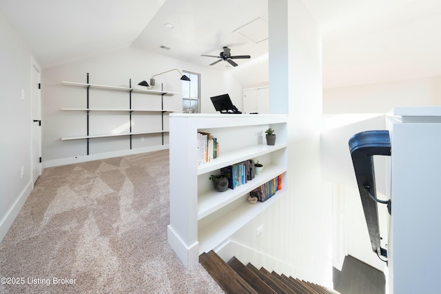 interior space with a ceiling fan, carpet, visible vents, baseboards, and vaulted ceiling