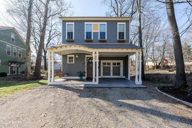 view of front of house featuring a garage, gravel driveway, and a porch