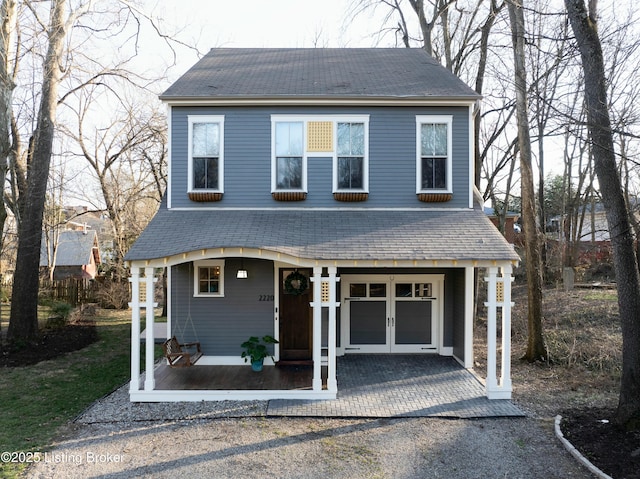 view of front of home featuring an attached garage, french doors, driveway, and a shingled roof