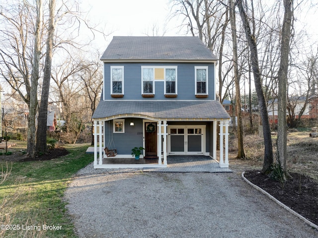 view of front of property with driveway, french doors, roof with shingles, covered porch, and a garage