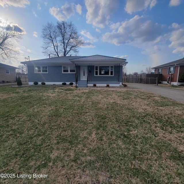 view of front of home featuring a front yard, fence, driveway, a standing seam roof, and metal roof