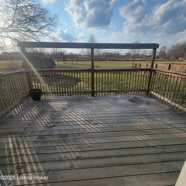 deck with a storage shed, a yard, a rural view, and an outbuilding