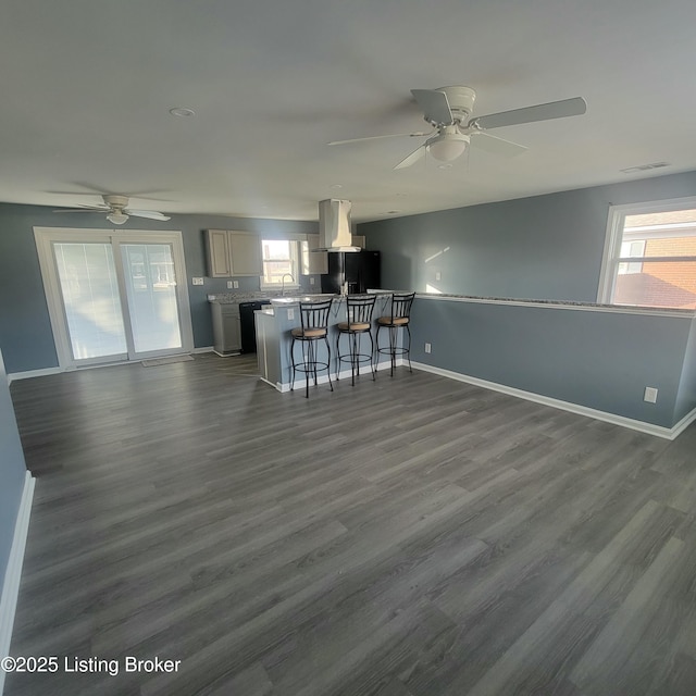 unfurnished living room with visible vents, baseboards, ceiling fan, and dark wood-style flooring