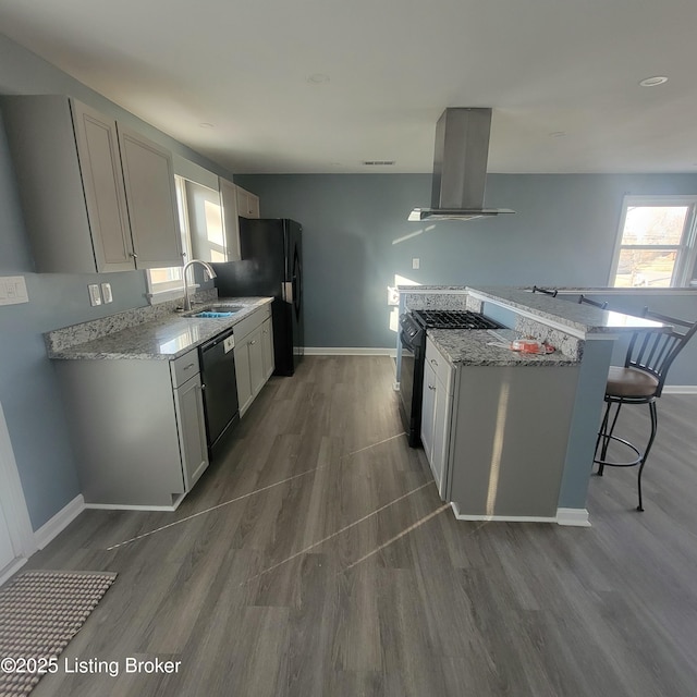 kitchen featuring a sink, black appliances, light stone counters, and island range hood