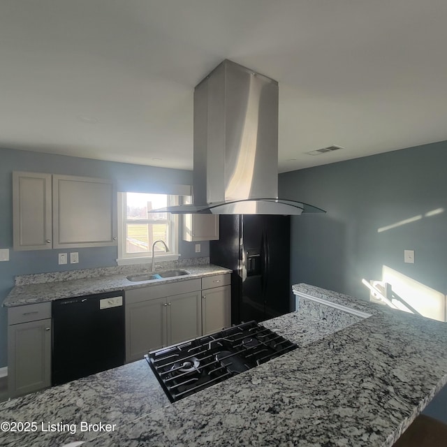 kitchen with visible vents, black appliances, a sink, island exhaust hood, and light stone countertops