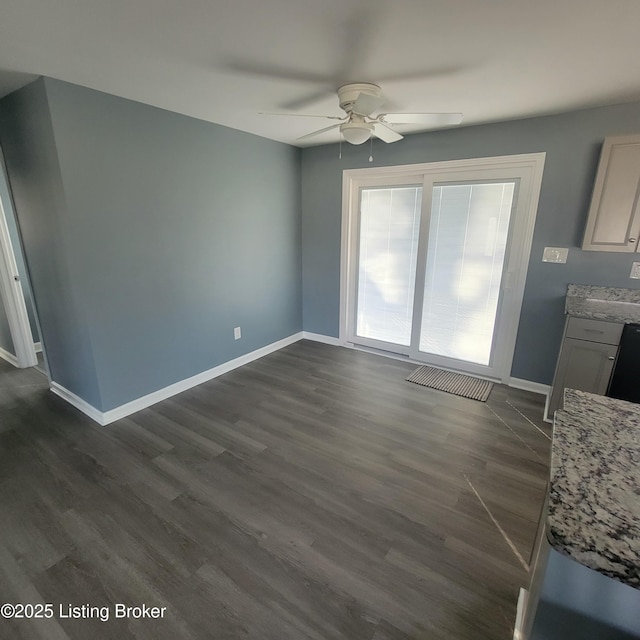 unfurnished living room with baseboards, dark wood-type flooring, and ceiling fan