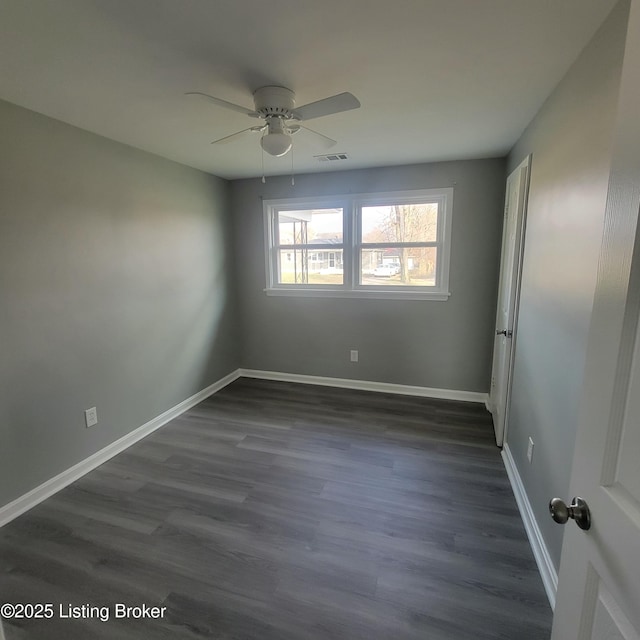 spare room featuring visible vents, baseboards, ceiling fan, and dark wood finished floors