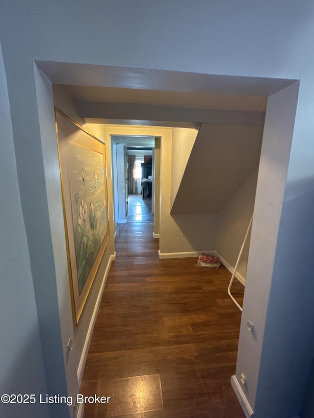 hallway featuring dark wood-type flooring and baseboards