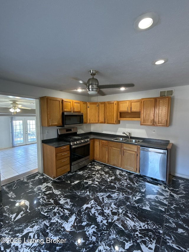 kitchen with dark countertops, a ceiling fan, appliances with stainless steel finishes, and a sink