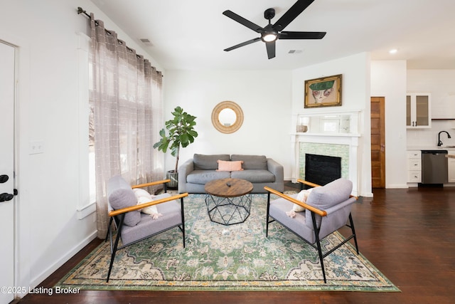 living area featuring visible vents, a fireplace, ceiling fan, and dark wood-style flooring