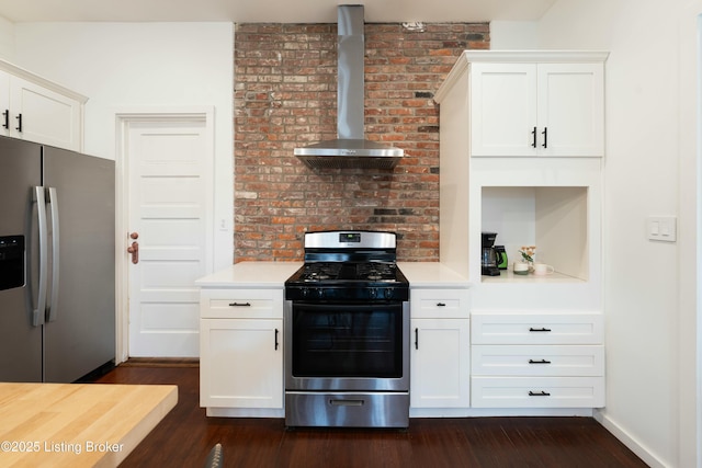 kitchen with dark wood-type flooring, appliances with stainless steel finishes, wall chimney exhaust hood, and light countertops