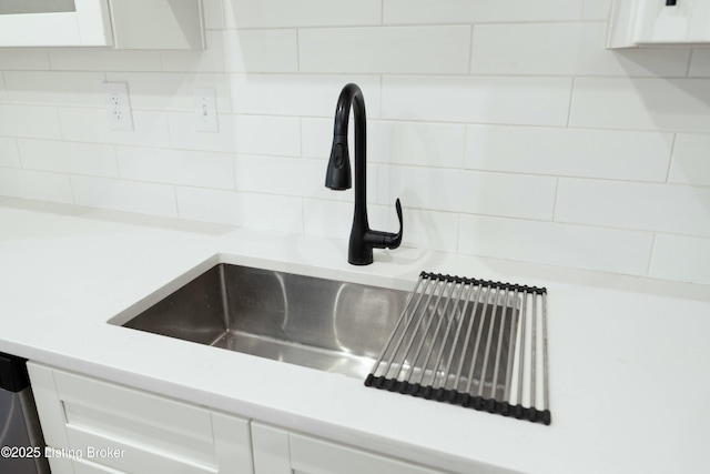 room details featuring decorative backsplash, white cabinetry, light countertops, and a sink