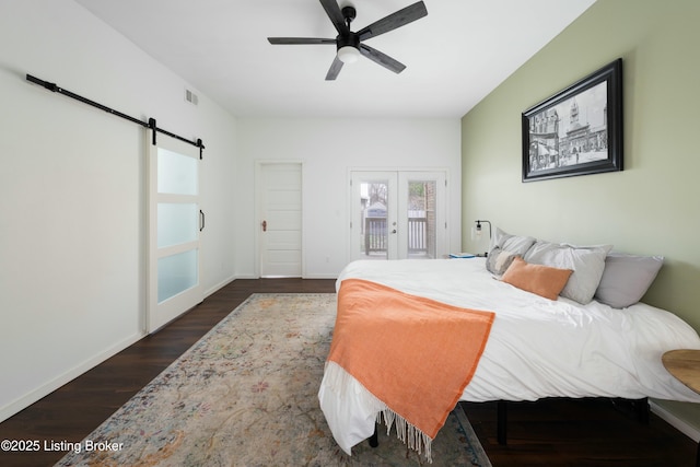 bedroom with visible vents, dark wood-style floors, a barn door, baseboards, and access to exterior