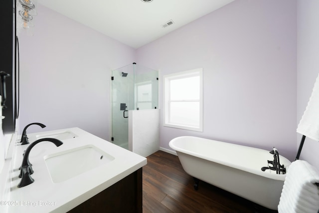 full bath with visible vents, a shower stall, wood finished floors, a soaking tub, and a sink