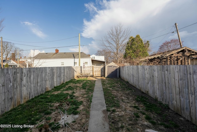 view of yard featuring an outbuilding, a storage shed, and a fenced backyard