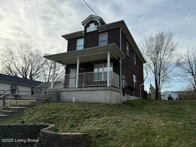 view of front of home with stairway, a porch, and a front lawn