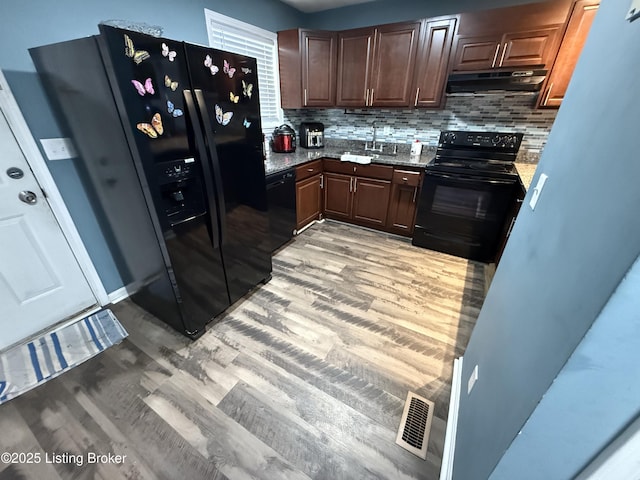 kitchen with black appliances, light wood-style flooring, visible vents, and under cabinet range hood