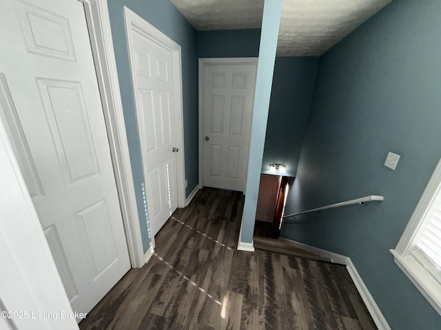 hallway featuring wood finished floors, baseboards, and a textured ceiling