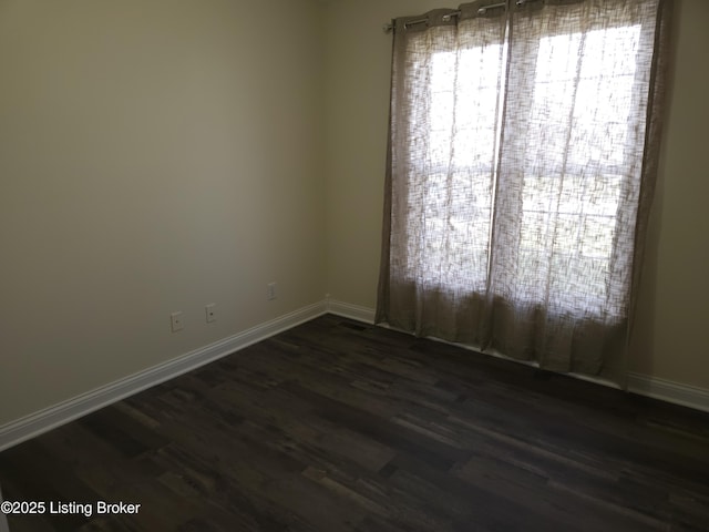 unfurnished room featuring baseboards and dark wood-style flooring