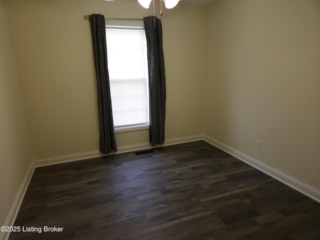 empty room with baseboards, a healthy amount of sunlight, and dark wood-style flooring