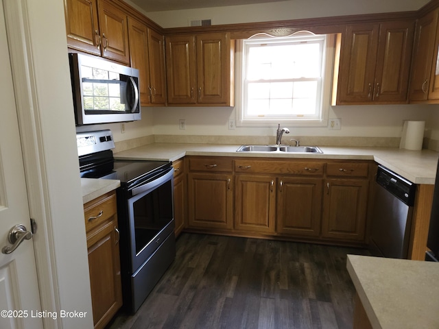 kitchen featuring visible vents, dark wood-style floors, brown cabinetry, stainless steel appliances, and a sink