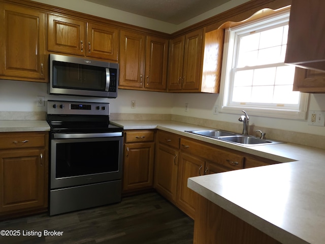 kitchen with brown cabinetry, appliances with stainless steel finishes, light countertops, and a sink