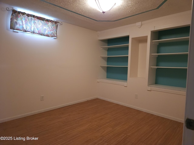 empty room featuring wood finished floors, baseboards, and a textured ceiling