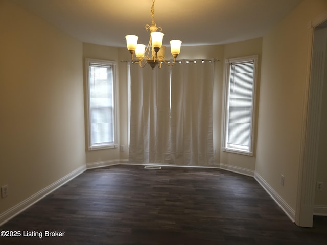 empty room with baseboards, a notable chandelier, and dark wood-style flooring