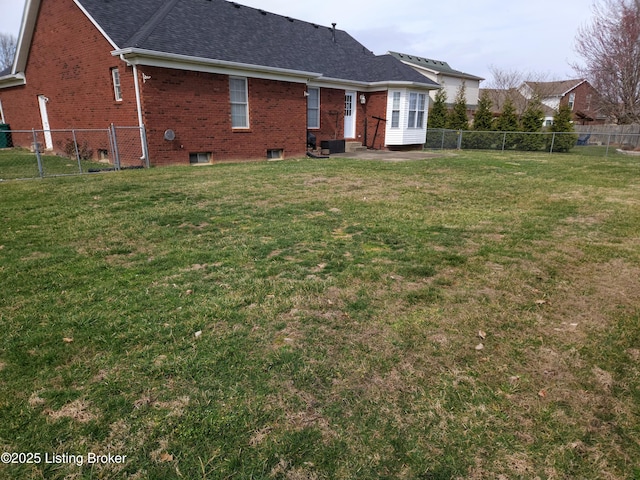 back of house with brick siding, a lawn, and a fenced backyard