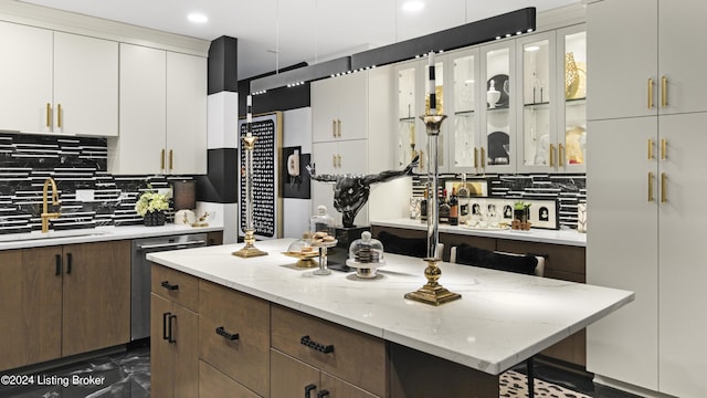 kitchen with tasteful backsplash, a kitchen island, stainless steel dishwasher, white cabinets, and a sink