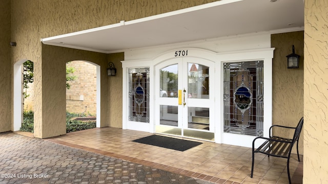 entrance to property featuring stucco siding, french doors, and a patio