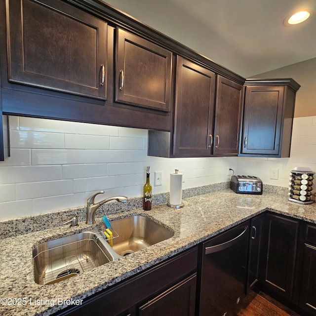 kitchen with light stone counters, dishwashing machine, a sink, and decorative backsplash