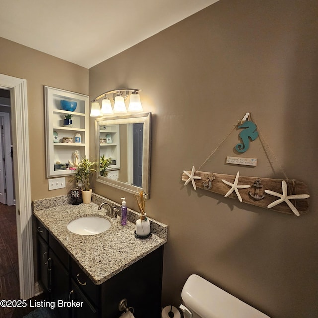 bathroom with toilet, vanity, and wood finished floors