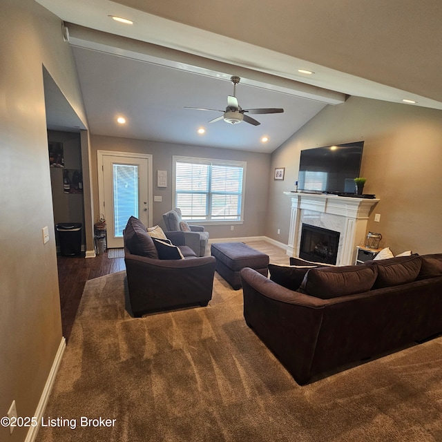 living room featuring baseboards, lofted ceiling with beams, a fireplace, wood finished floors, and a ceiling fan