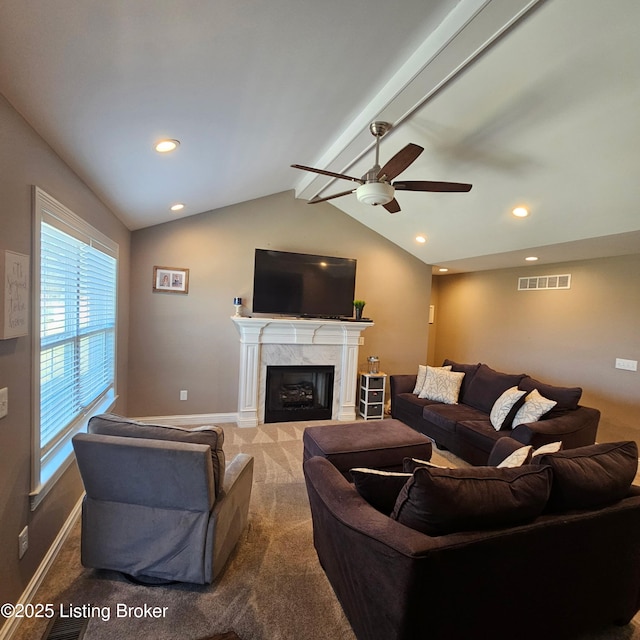 carpeted living area with a high end fireplace, visible vents, baseboards, lofted ceiling with beams, and a ceiling fan