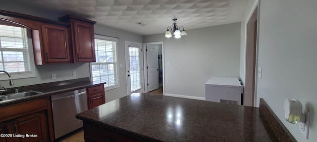 kitchen with a sink, stainless steel dishwasher, dark countertops, and a healthy amount of sunlight