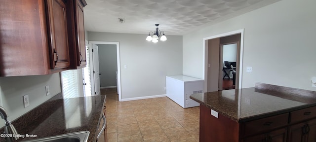 kitchen featuring visible vents, pendant lighting, a sink, baseboards, and a chandelier