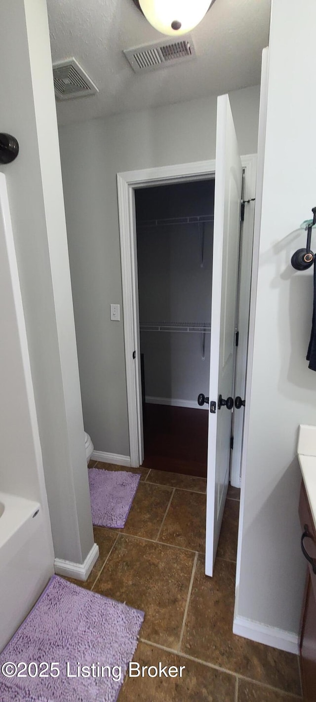 bathroom featuring visible vents, baseboards, vanity, and stone finish floor