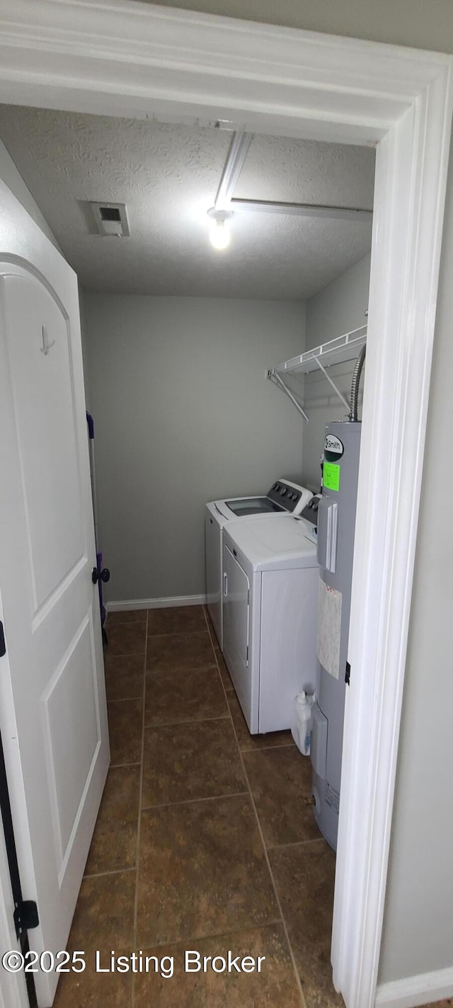 laundry room with visible vents, laundry area, water heater, a textured ceiling, and washer and clothes dryer