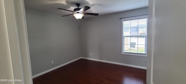 spare room featuring a ceiling fan, baseboards, and dark wood-style flooring